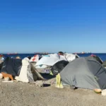 Tiendas de campaña improvisadas en una playa de Ceuta tras la llegada masiva de personas migrantes.