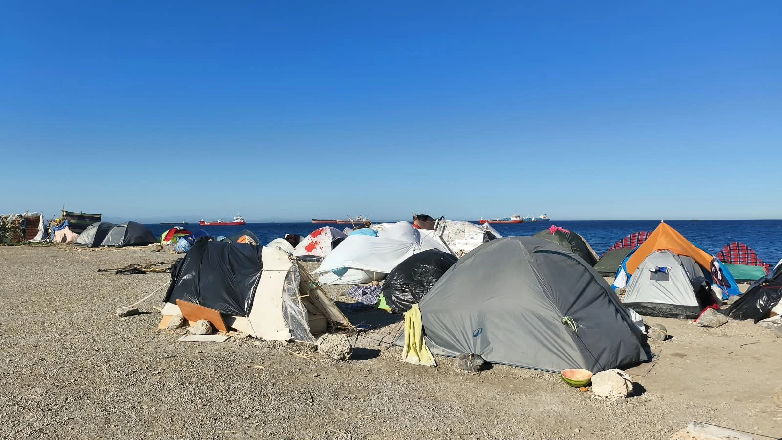 Tiendas de campaña improvisadas en una playa de Ceuta tras la llegada masiva de personas migrantes.